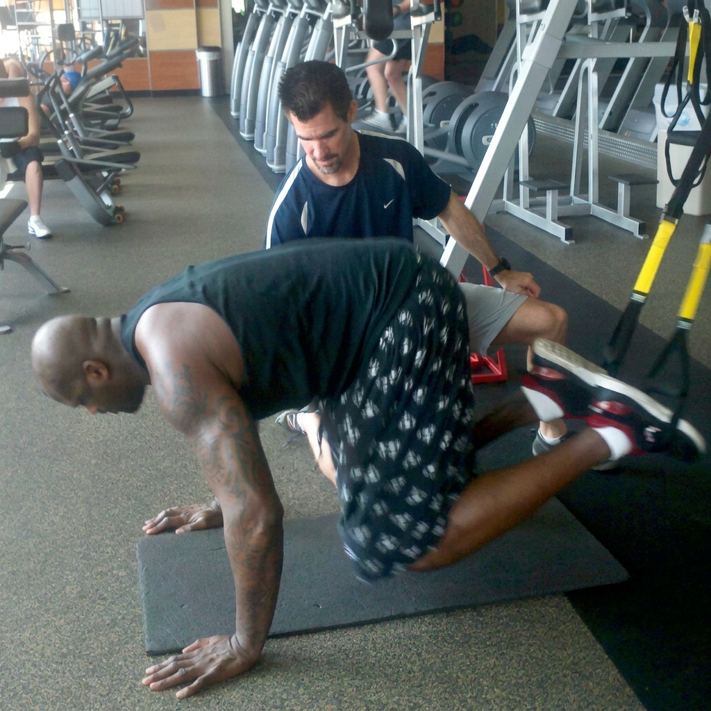 Jim Cotta training Shaquille O'Neal in the gym, coaching his conditioning during a suspension-trainer workout
